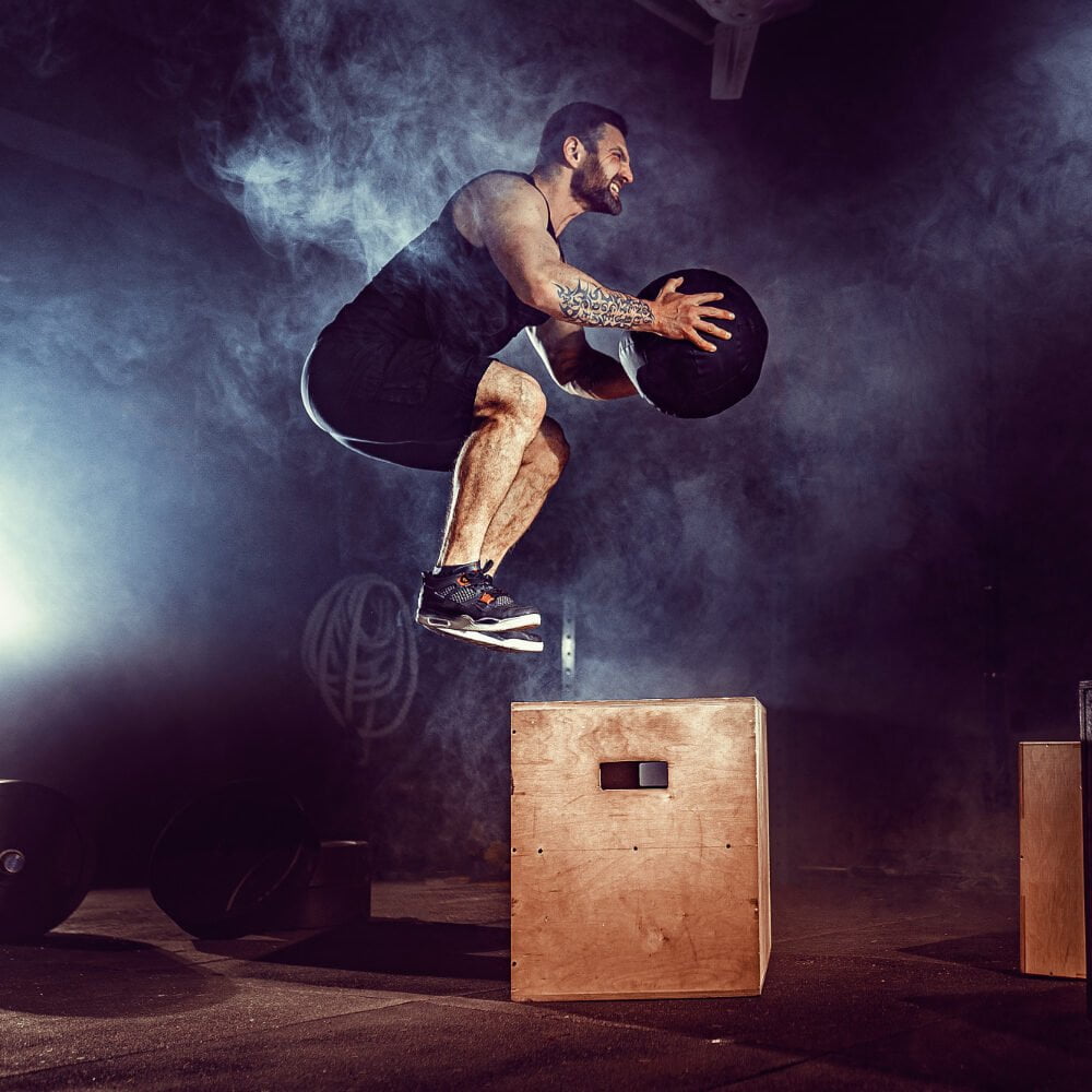 Fit Tattoed Bearded Man Jumping Onto Box As Part Exercise Routine Man Doing Box Jump Gym Athlete Is Performing Box Jumps