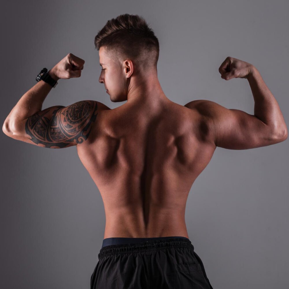 Sporty Handsome Bodybuilder Guy With Muscular Rear Back Poses Shows Muscle Against Dark Background Studio