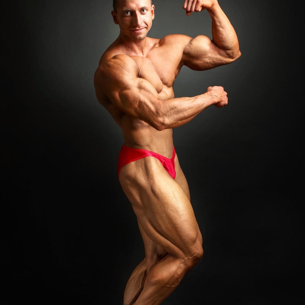 Studio Shot Male Bodybuilder Posing Showing Biceps Legs With Black Background